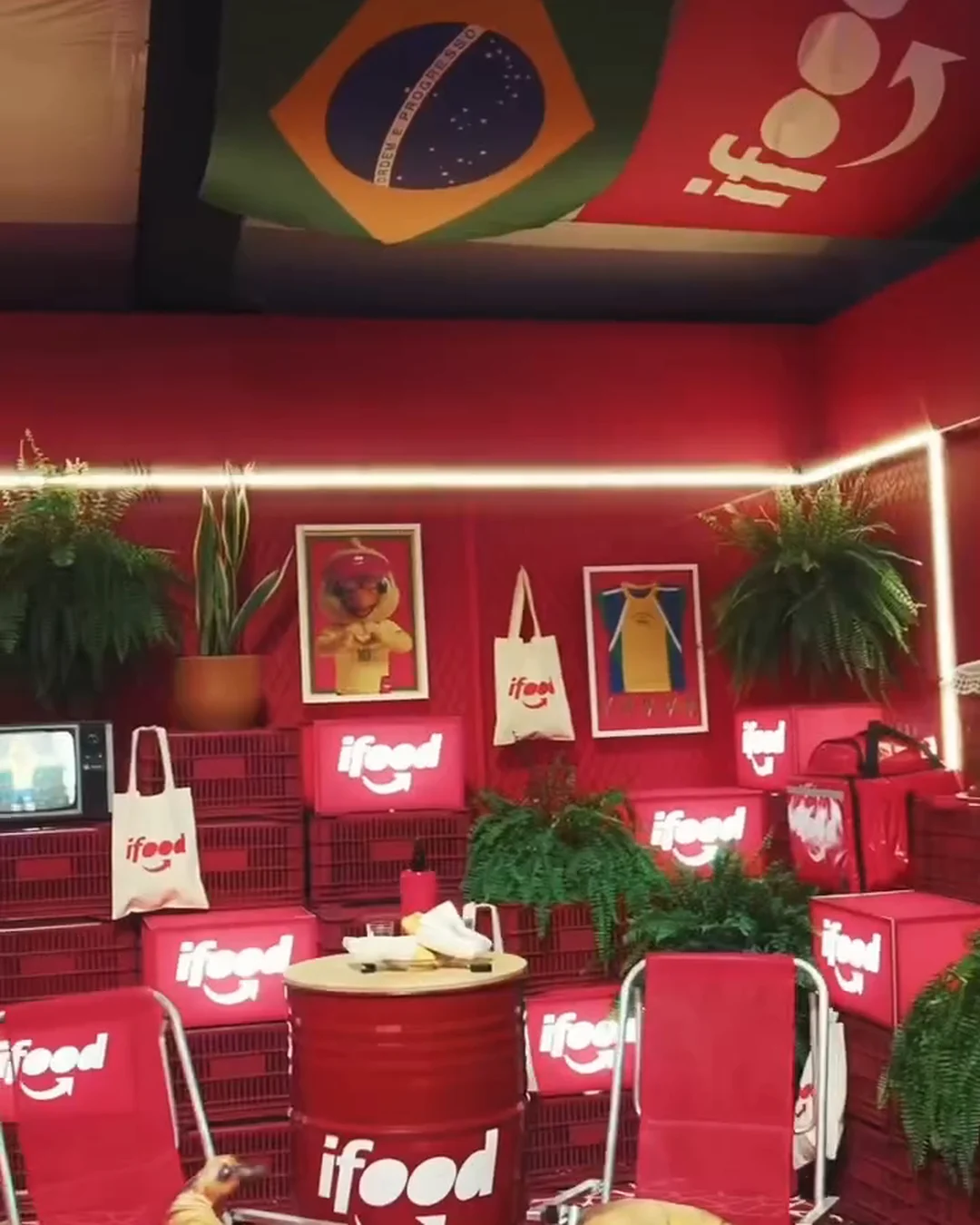 Lounge do iFood realizado com mobiliário, grafismos, plantas e objetos da marca